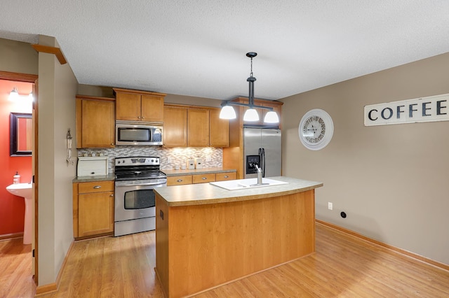 5108 Harvest Curv, Mayer, MN 55360 - kitchen with an island with sink, a sink, light wood-style flooring, backsplash, and stainless steel appliances