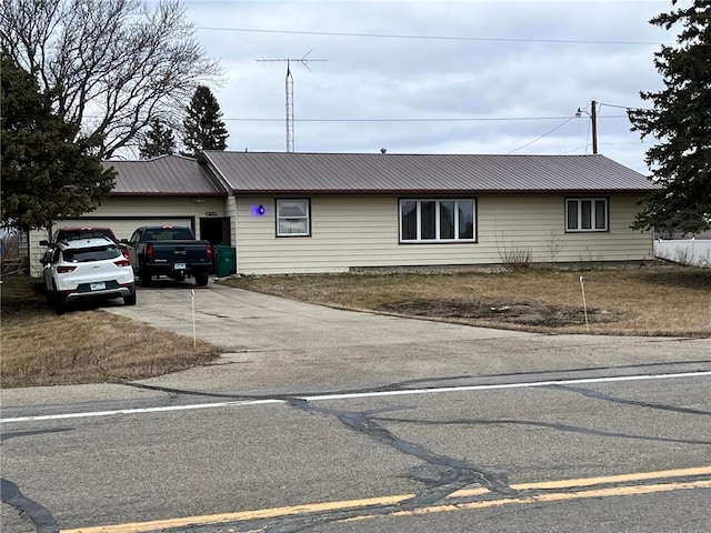 single story home with metal roof, driveway, and an attached garage