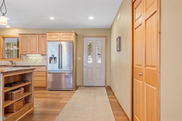 kitchen featuring light brown cabinetry, decorative backsplash, stainless steel fridge, and light wood-style floors