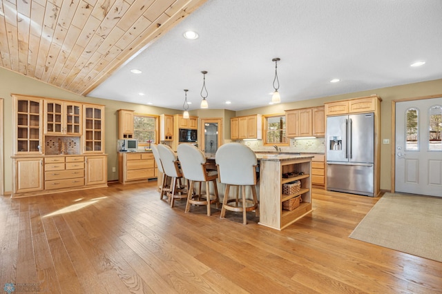 kitchen with a large island, appliances with stainless steel finishes, light brown cabinetry, light wood-type flooring, and open shelves