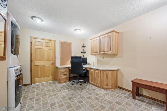 home office with a textured ceiling, stacked washing maching and dryer, and baseboards