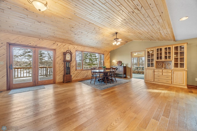 unfurnished dining area featuring vaulted ceiling, light wood finished floors, wood ceiling, and wooden walls