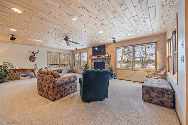 carpeted living room featuring a fireplace, visible vents, wood ceiling, ceiling fan, and wooden walls