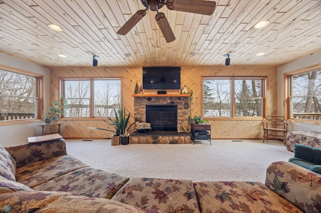 carpeted living area with wooden ceiling, wooden walls, a fireplace, and recessed lighting