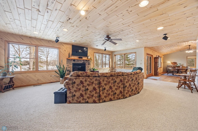 living area featuring carpet, wood ceiling, wood walls, and a stone fireplace