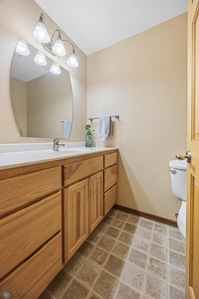 bathroom with toilet, baseboards, a textured ceiling, and vanity