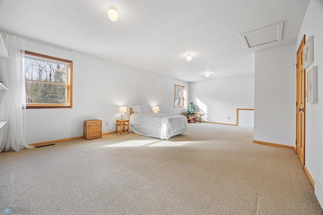 unfurnished bedroom with attic access, carpet, visible vents, and a textured ceiling