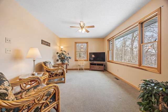 carpeted living room featuring a ceiling fan, visible vents, a textured ceiling, and baseboards