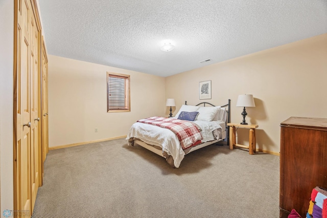 bedroom featuring baseboards, carpet flooring, visible vents, and a textured ceiling