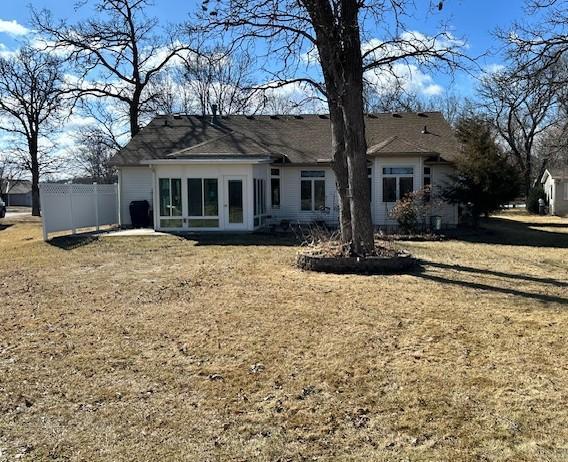 rear view of house featuring a yard and fence