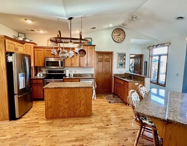 kitchen with light wood finished floors, visible vents, appliances with stainless steel finishes, a kitchen island, and a peninsula