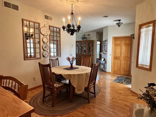 dining area with light wood-style floors, baseboards, and visible vents