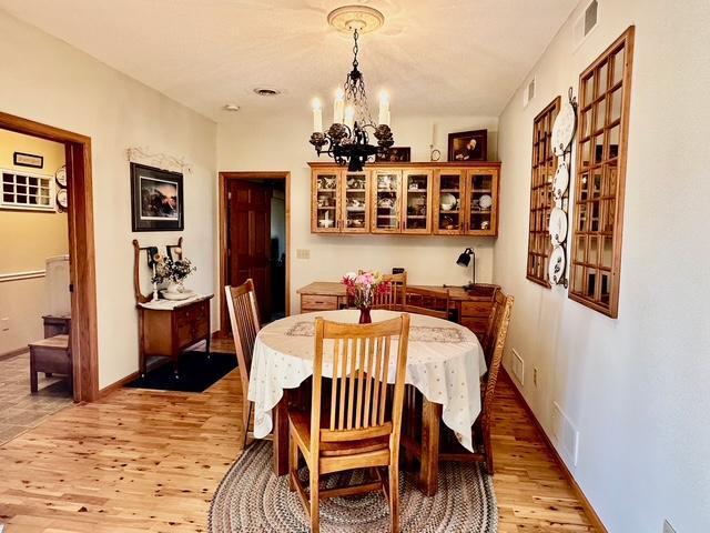 dining room featuring light wood-type flooring, visible vents, and an inviting chandelier