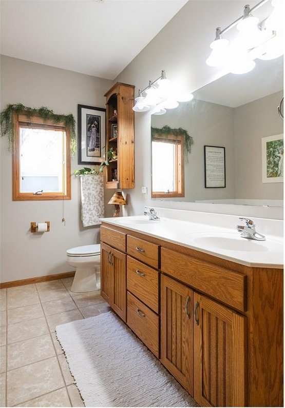 full bathroom featuring double vanity, toilet, a sink, and tile patterned floors