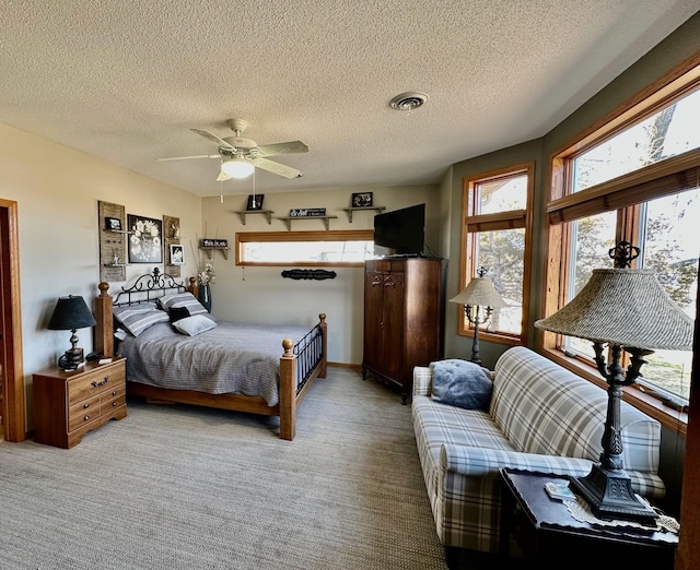 carpeted bedroom featuring ceiling fan, visible vents, and a textured ceiling