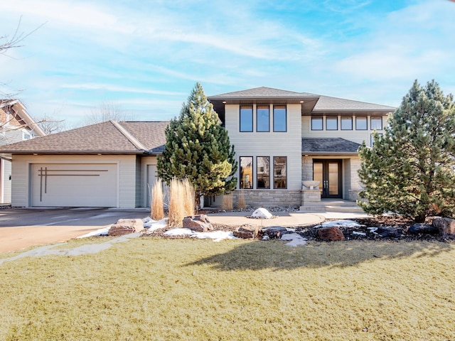 view of front of property with french doors, a shingled roof, a front yard, a garage, and driveway