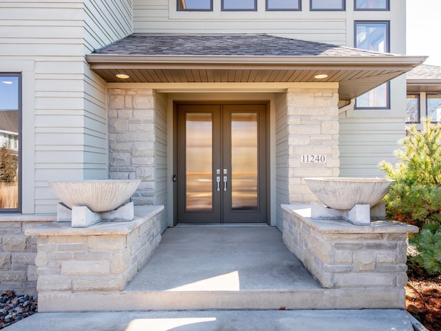 property entrance featuring stone siding, roof with shingles, and french doors