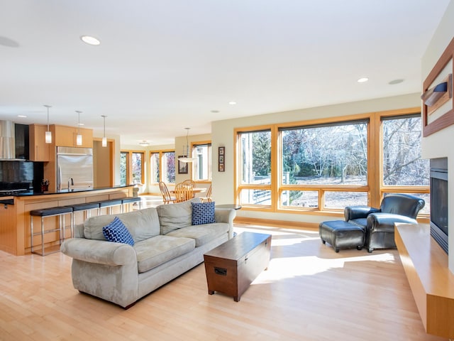 living room featuring recessed lighting, a glass covered fireplace, and light wood-style flooring