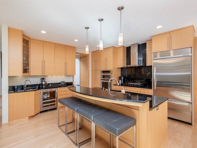 kitchen with beverage cooler, light brown cabinetry, appliances with stainless steel finishes, and wall chimney exhaust hood