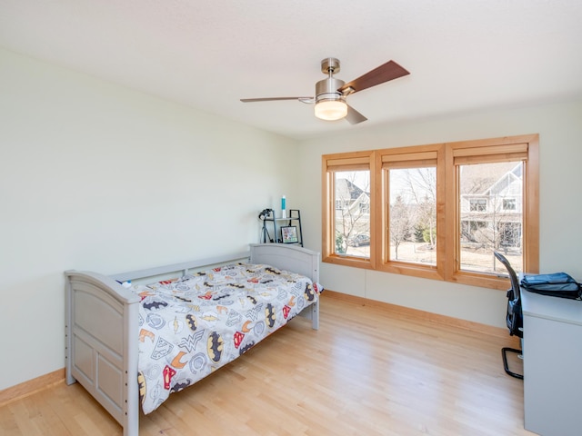 bedroom with a ceiling fan, baseboards, and light wood finished floors