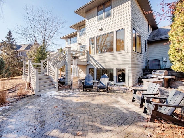 rear view of property with stairs, a patio area, and a fire pit