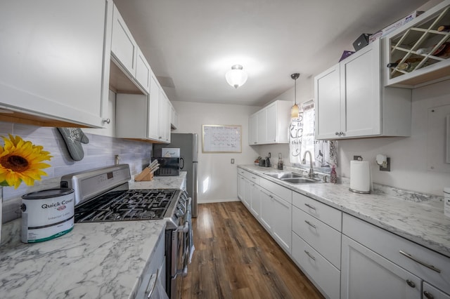 kitchen featuring dark wood-style flooring, a sink, white cabinets, stainless steel gas range, and decorative backsplash