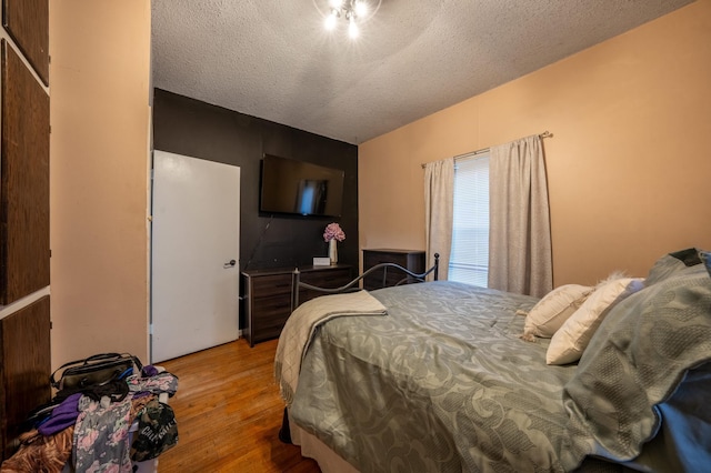 bedroom with a textured ceiling and wood finished floors