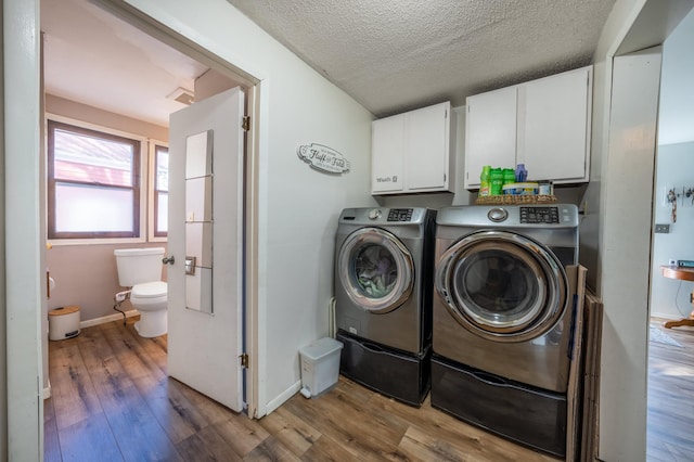 clothes washing area featuring cabinet space, baseboards, washer and clothes dryer, wood finished floors, and a textured ceiling