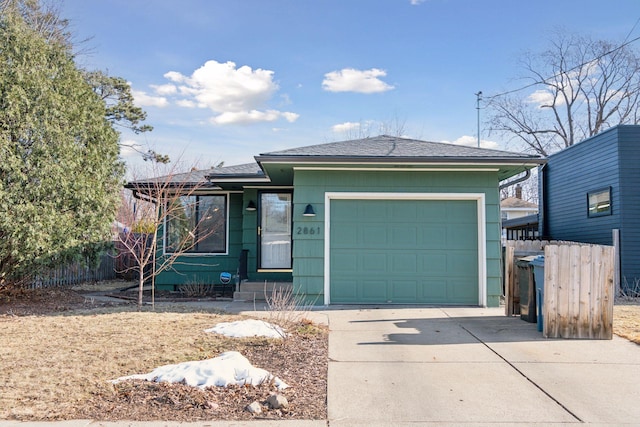 view of front facade with roof with shingles, concrete driveway, an attached garage, and fence