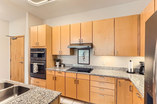 kitchen featuring light stone counters, light brown cabinets, light tile patterned flooring, black appliances, and under cabinet range hood