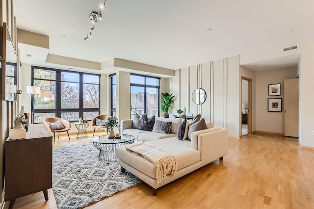 living area featuring visible vents, baseboards, rail lighting, and light wood finished floors