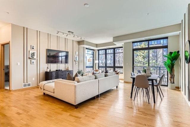 living area featuring rail lighting, baseboards, visible vents, and light wood finished floors