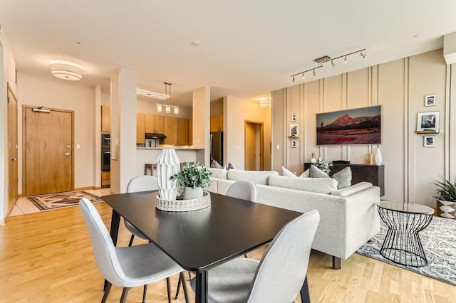 dining space featuring track lighting and light wood-style flooring