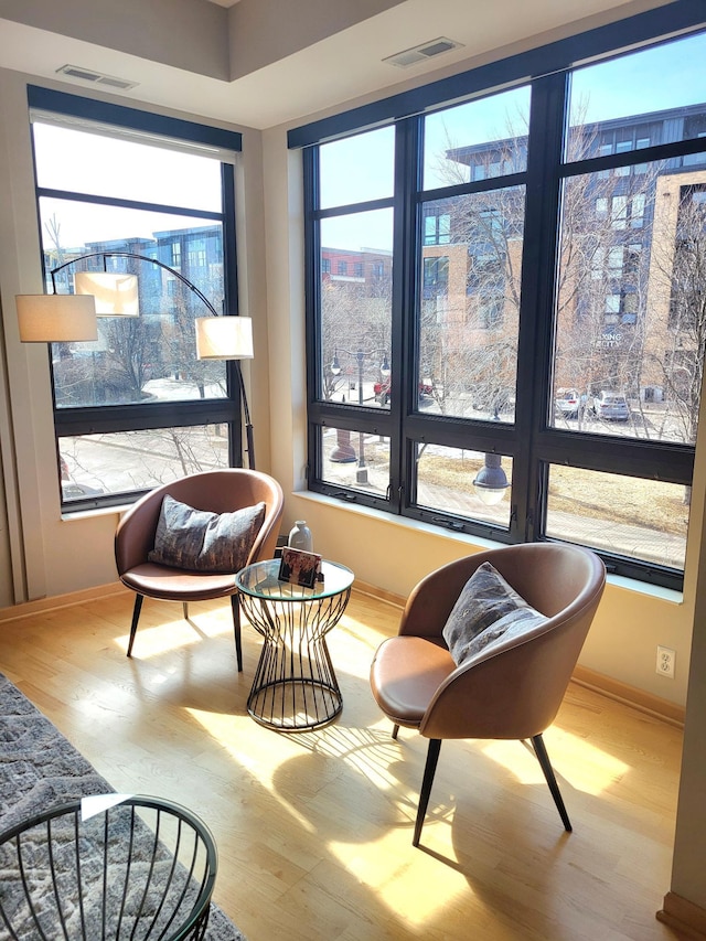 living area featuring visible vents, baseboards, and wood finished floors