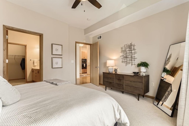 bedroom featuring baseboards, visible vents, ceiling fan, a walk in closet, and light colored carpet