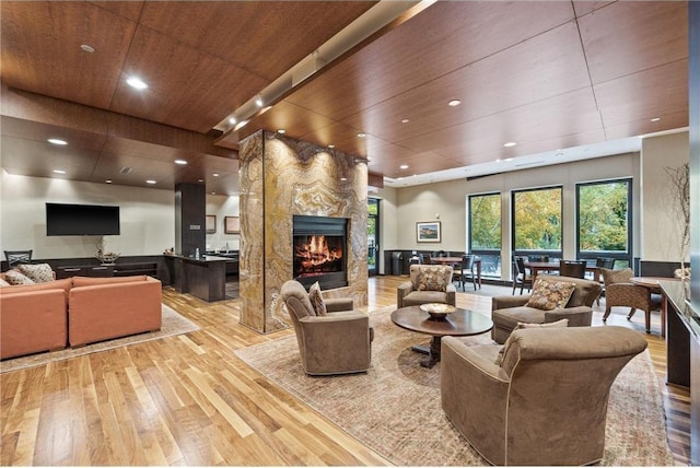 living room featuring recessed lighting, a premium fireplace, wood ceiling, and hardwood / wood-style flooring