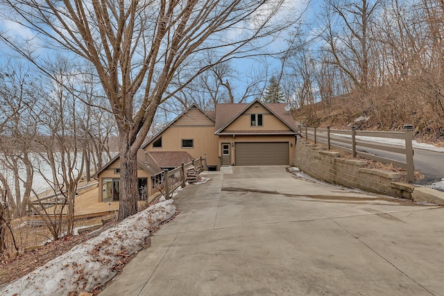 view of front facade with a shingled roof, concrete driveway, fence, and an attached garage