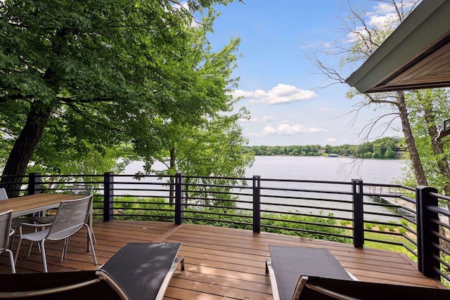 wooden terrace featuring outdoor dining area and a water view