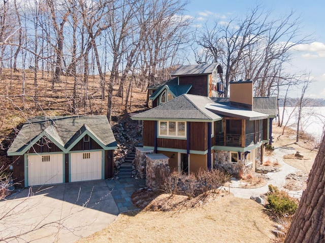 view of front of house with a sunroom, stone siding, a detached garage, and an outdoor structure