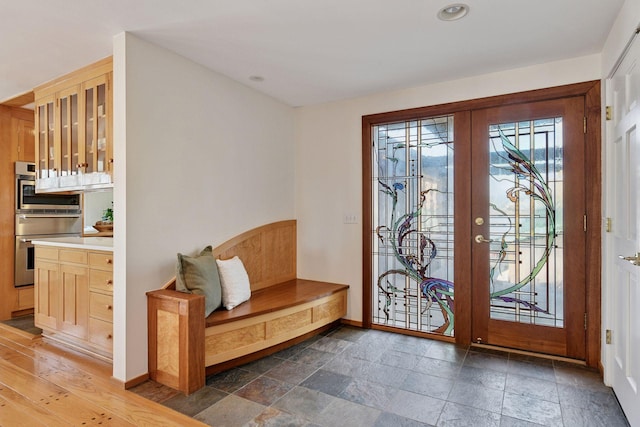 entrance foyer with stone finish flooring, baseboards, and french doors