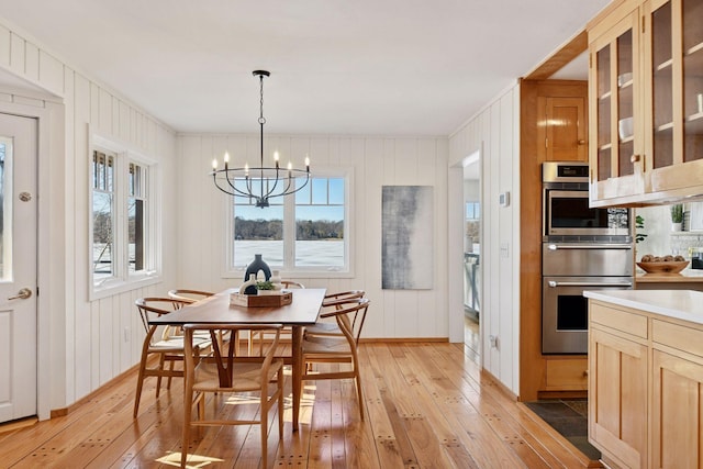 dining space with a notable chandelier, light wood-style flooring, and a healthy amount of sunlight