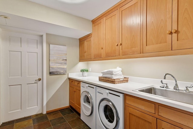 laundry area with cabinet space, baseboards, independent washer and dryer, stone finish flooring, and a sink