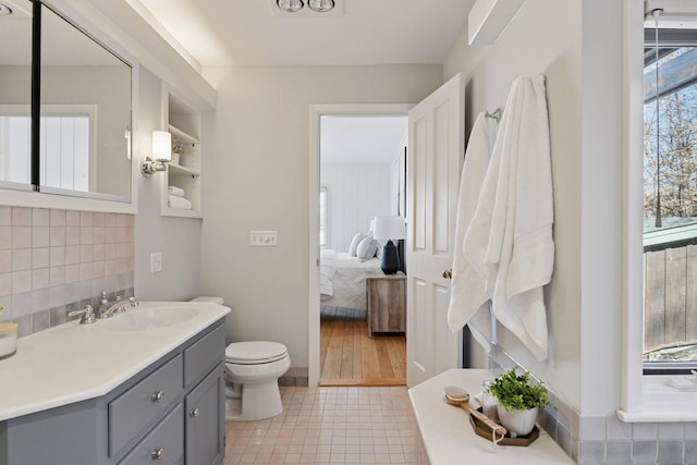 ensuite bathroom with tasteful backsplash, toilet, ensuite bathroom, vanity, and tile patterned floors