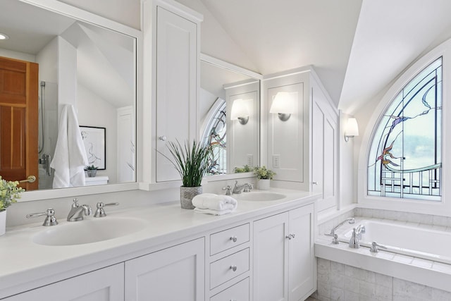 full bath with vaulted ceiling, double vanity, a sink, and a garden tub