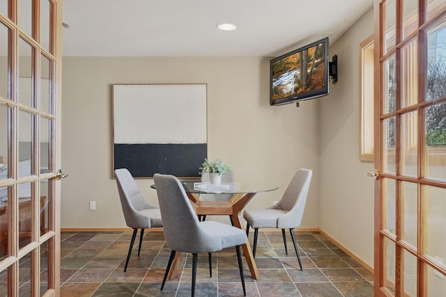 dining room featuring french doors, stone finish floor, and baseboards