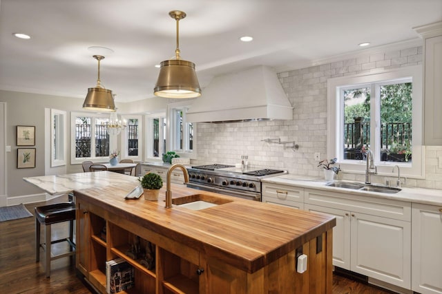 kitchen with range with two ovens, a sink, wood counters, and custom exhaust hood