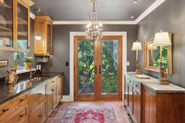 doorway with baseboards, ornamental molding, an inviting chandelier, french doors, and a sink