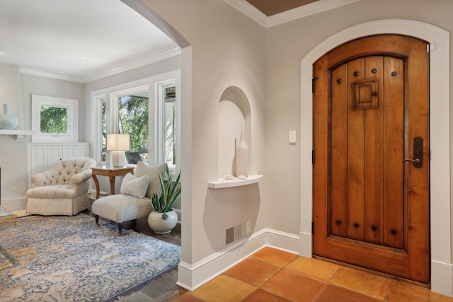 entrance foyer featuring baseboards, arched walkways, visible vents, and crown molding