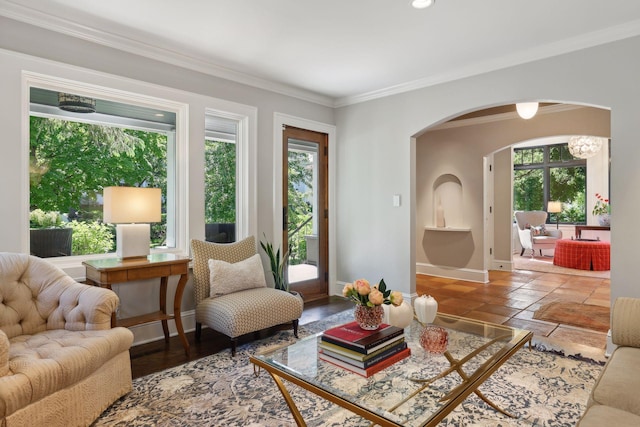 living room featuring baseboards, arched walkways, stone tile floors, and crown molding