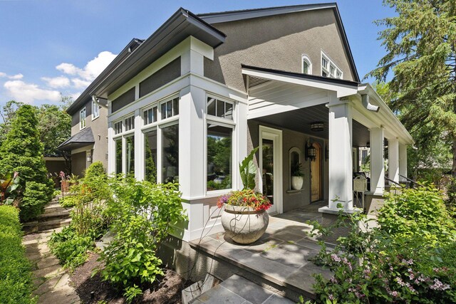 property entrance with covered porch and stucco siding